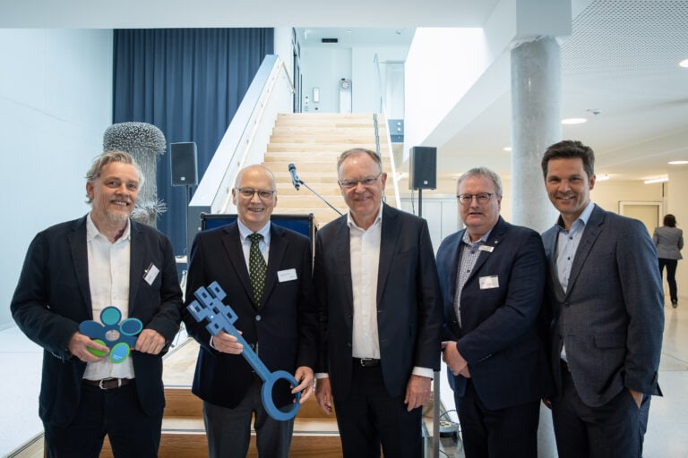 Der Architekt übergibt den Schlüssel an den Geschäftsführer im Beisein der Grußwortredner.